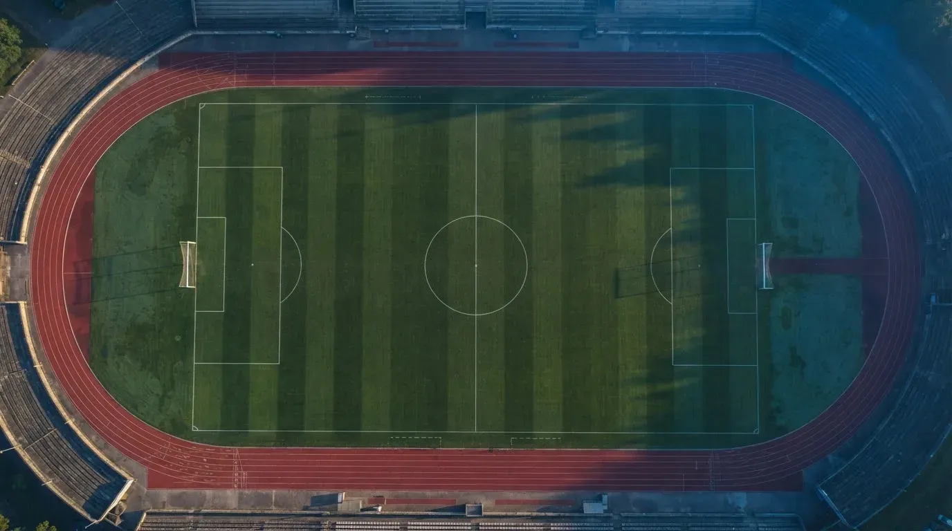 Ein Fussballplatz von oben gesehen, die Linien bilden ein helles Muster auf dem Rasen, Drohnenperspektive in der Morgendämmerung.