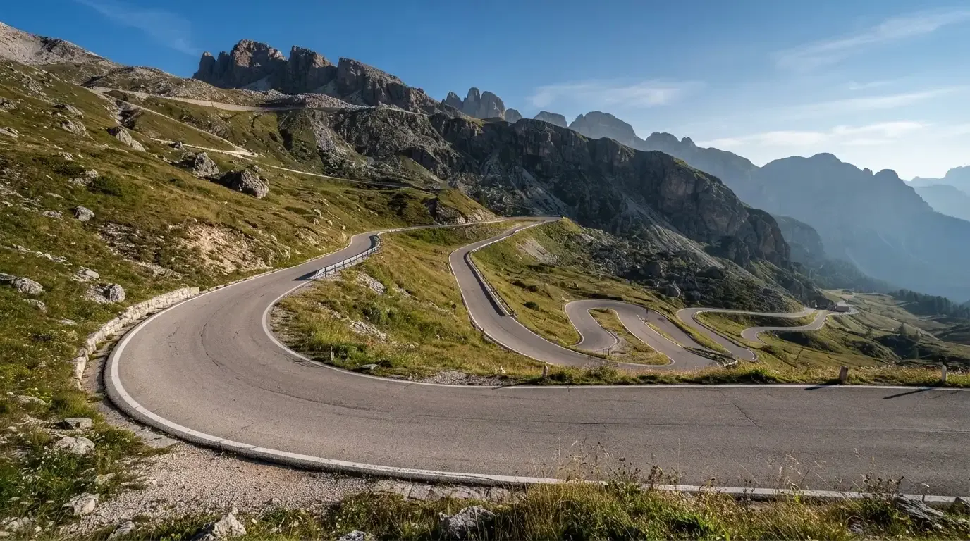 Eine Passstrasse zieht sich in Kehren einen Alpenhang hinauf, kein Fahrzeug ist zu sehen.