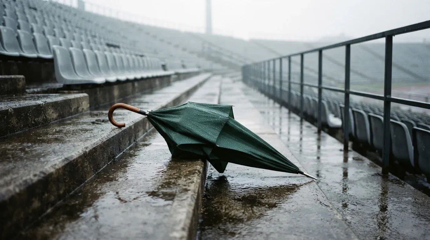 Ein Regenschirm liegt auf einer nassen Treppe zwischen leeren Zuschauerrängen.
